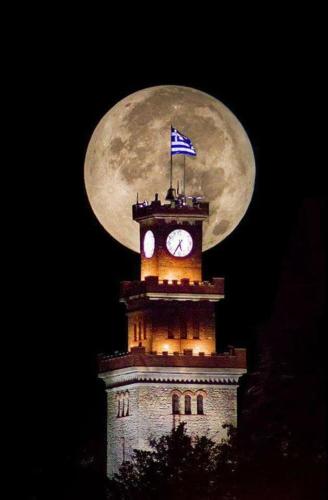 a clock tower with a flag on top of it at 4-seasons pool villa near Meteora in Tríkala