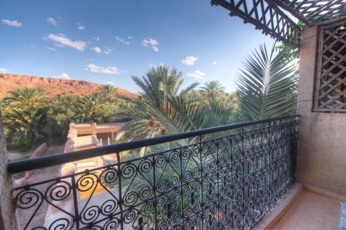 a balcony with a fence and palm trees at Gite Tamlli in Aoufous