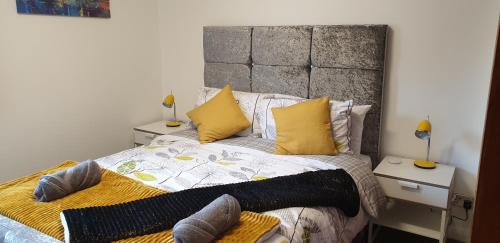 a bedroom with a large bed with yellow pillows at The Beach Apartment, near Outlander location in Kirkcaldy