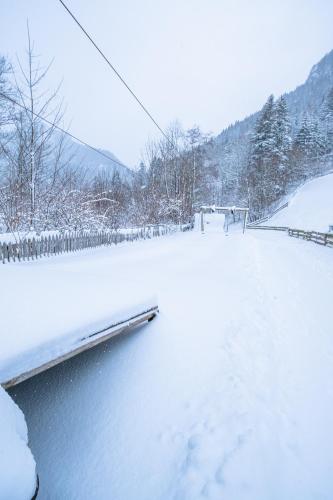 a snow covered field with a fence and a river at Kinderhotel Appelhof in Mürzsteg