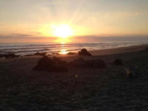a sunset on a beach with rocks in the sand at Las Villas, Villa Alegria,Troncones in Troncones