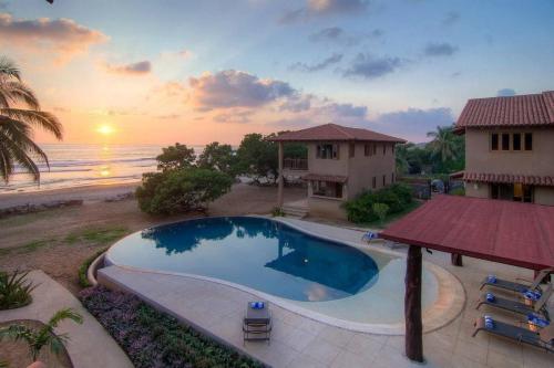 a swimming pool in front of a house and the ocean at Las Villas, Villa Alegria,Troncones in Troncones