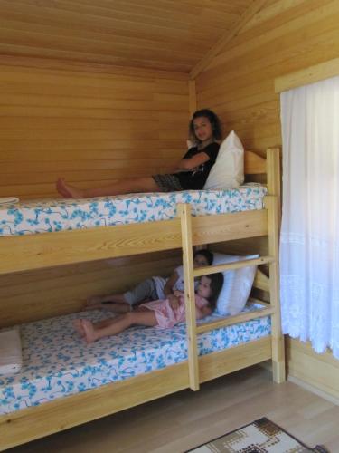a woman and two children in a bunk bed at Baris Pension & Bungalows in Cıralı