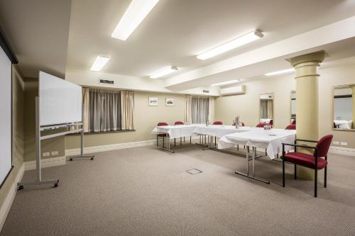 a conference room with white tables and red chairs at Launceston Central Apartment Hotel Official in Launceston