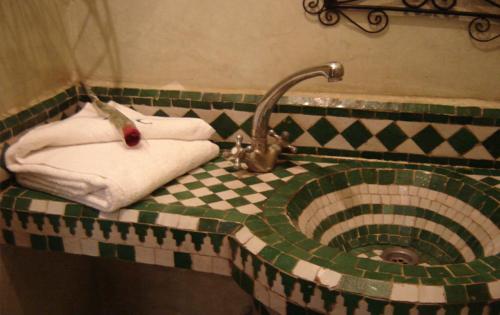 a bathroom sink with towels and a faucet at Riad Hôtel Belleville Marrakech in Marrakech