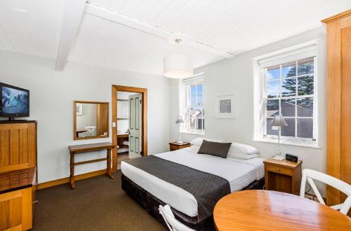 1 dormitorio con cama, mesa y TV en Seacombe House Motor Inn Port Fairy en Port Fairy