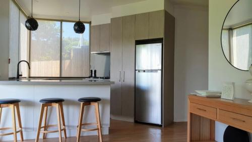 a kitchen with a stainless steel refrigerator and bar stools at Number 9 Leisure Stay in Port Campbell