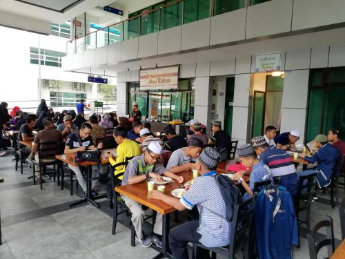 um grupo de pessoas sentadas à mesa a comer em Shah Suites Vista Alam em Shah Alam