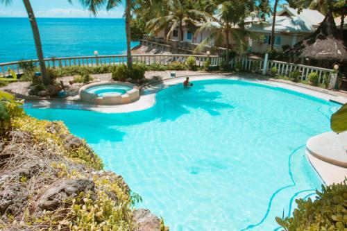 a swimming pool with the ocean in the background at Estaca Bay Gardens Conference Resort powered by Cocotel in Compostela