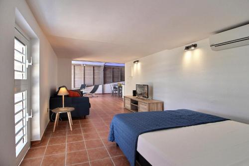 1 dormitorio con 1 cama y sala de estar en Appartement THOMANA , jacuzzi privé, plage à 200 m, en Le Moule
