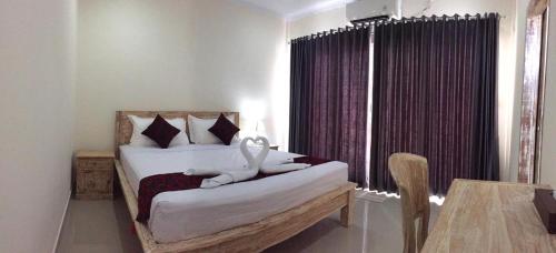 a bedroom with a bed and a table and a window at Laksmi Guest House in Canggu
