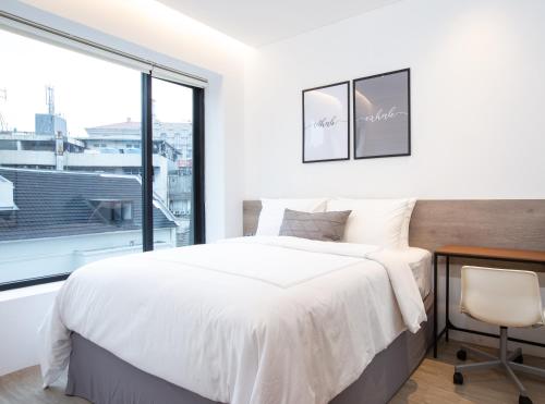 a white bedroom with a bed and a window at Ariama Serviced Residence in Jakarta
