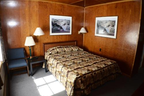 a bedroom with a bed and a chair and two pictures at The Willows Motel in Wilbur