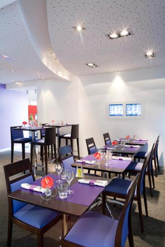 a dining room with tables and chairs with wine glasses at Novotel Amiens Pôle Jules Verne in Boves