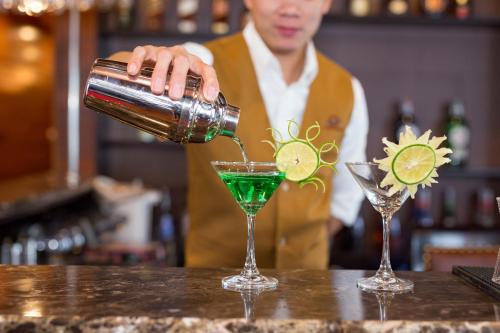 a bartender making a green drink in two martini glasses at V'Spirit Cruise in Ha Long