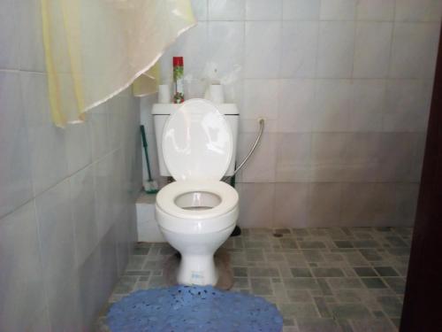a bathroom with a white toilet with a blue rug at CDH Backpackers in Mombasa