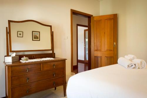 a bedroom with a wooden dresser and a mirror at Potteroo in Rothbury