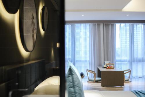 a hotel room with a bed and a table with chairs at SSAW Boutique Hotel Hangzhou Xixi Xin in Hangzhou