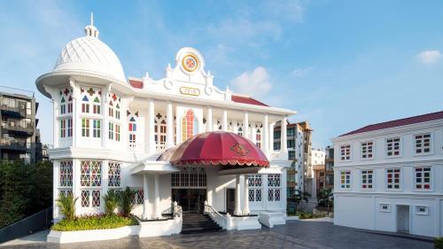 a large white building with a red awning at Mövenpick Myth Hotel Patong Phuket in Patong Beach