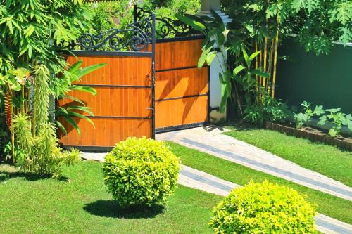 a wooden gate in a garden with two bushes at Villa 252 Kosgoda in Kosgoda