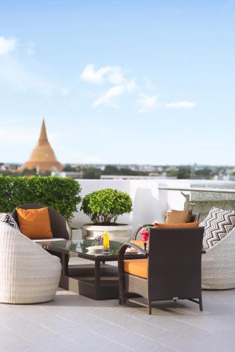 a patio with chairs and a table on a balcony at Mida Grande Hotel Dhavaravati Nakhon Pathom - SHA PLUS in Nakhon Pathom