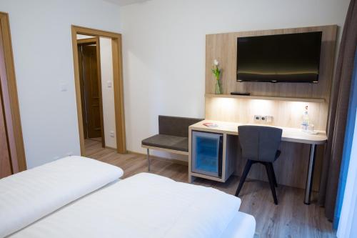 a hotel room with a bed and a desk and a tv at Gästehaus Hotel Wilms in Cologne