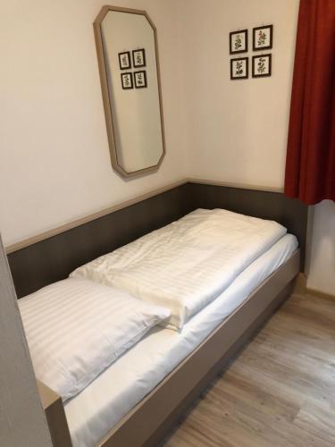 a small bed in a room with a mirror at Gästehaus Hotel Wilms in Cologne