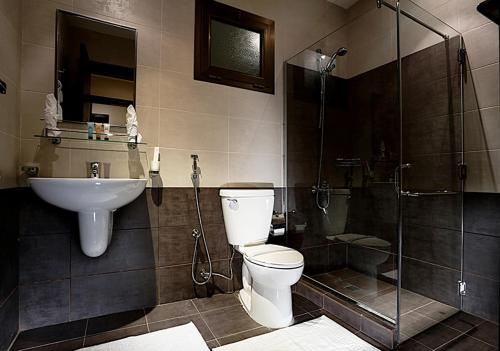 a bathroom with a toilet and a sink and a shower at Aswar Hotel Suites in Al Khobar