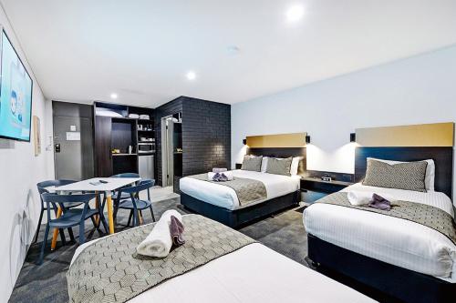 コフスハーバーにあるCBD Motor Innのベッド2台とテーブルが備わるホテルルームです。