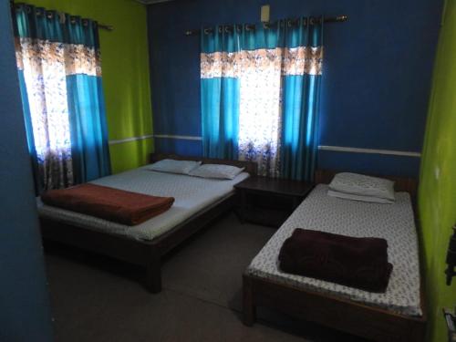 two beds in a room with blue and green at Vamoose Latpanchor Homestay in Mangpu