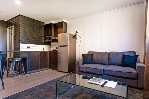 a living room with a couch and a kitchen at CBD Motor Inn in Coffs Harbour