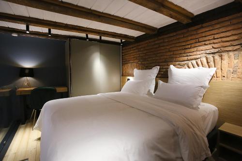 a bedroom with a large white bed with a brick wall at Paskunji Residence in Tbilisi City