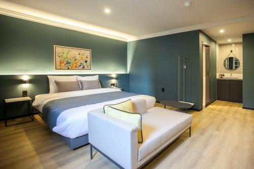 a bedroom with a large bed and a white couch at Browndot Hotel Masan Odong in Changwon