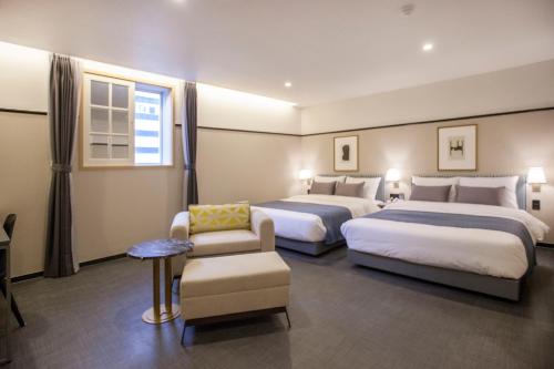 a hotel room with two beds and a chair at Browndot Hotel Masan Odong in Changwon