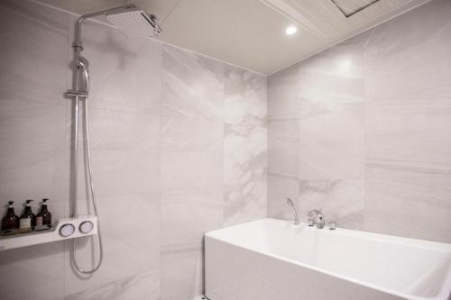 biała łazienka z prysznicem i wanną w obiekcie Browndot Hotel Masan Odong w mieście Changwon