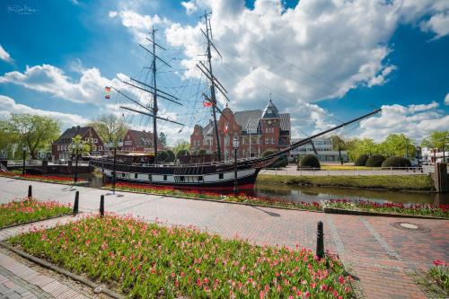 a boat is docked in a canal with flowers at Hotel Alte Werft in Papenburg