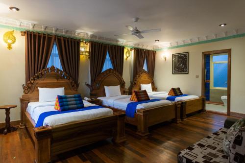 three beds in a room with wooden floors at Okay Palace Hotel in Phnom Penh