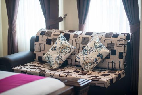 a couch with two pillows sitting in a room at Okay Palace Hotel in Phnom Penh