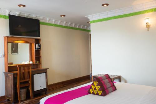 a bedroom with a bed and a tv on a wall at Okay Palace Hotel in Phnom Penh