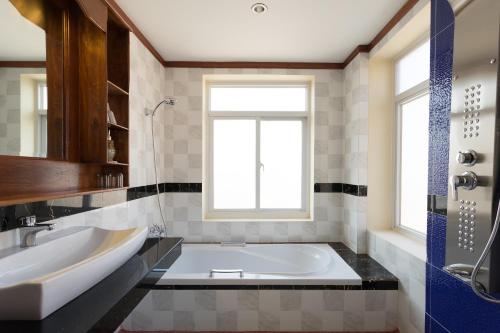 La salle de bains est pourvue d'une baignoire, d'un lavabo et d'une fenêtre. dans l'établissement Okay Palace Hotel, à Phnom Penh