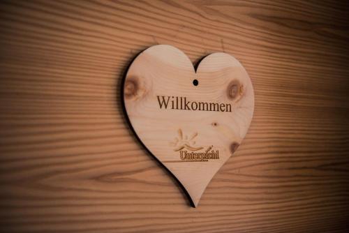 a wooden heart on a wooden table with the word willuminati at Natur Pur Hotel Unterpichl in Ultimo