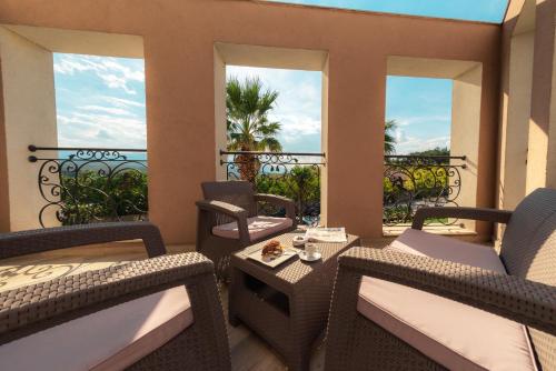 a balcony with wicker chairs and a table and windows at Mantar Spa Hotel in Marikostinovo