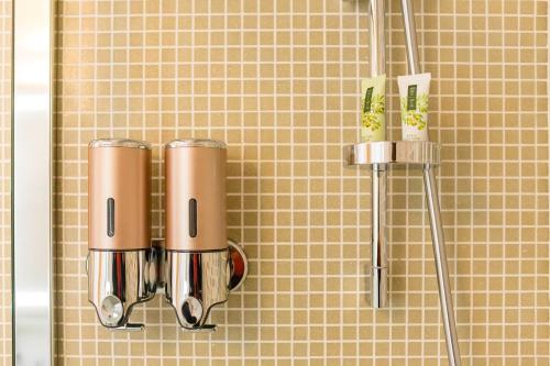 a shower with two brown and silver cups on a wall at Le Maestranze Deluxe Rooms in Sciacca