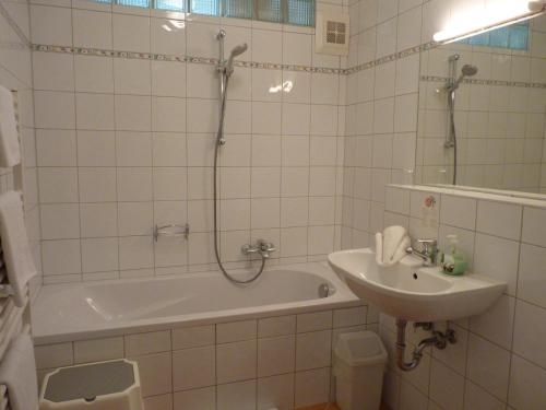 uma casa de banho com uma banheira, um lavatório e um chuveiro em Landhaus Strussnighof em Pörtschach am Wörthersee