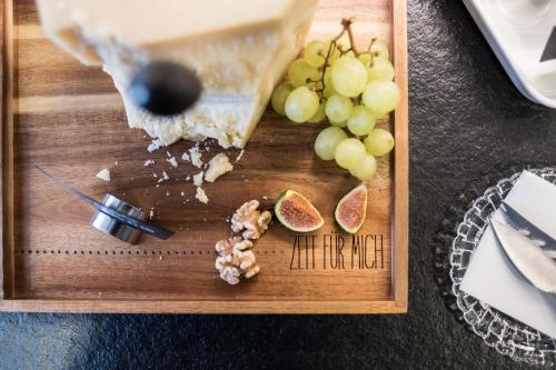 a wooden cutting board with grapes and a piece of cheese at Eriks Hotel in Fürholzen