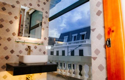 a bathroom with a sink and a window with a building at Tre Việt Tuy Hòa Hotel in Tuy Hoa