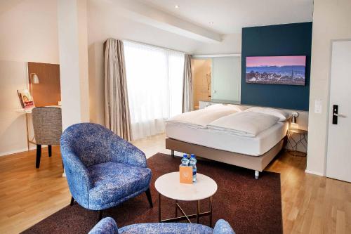 Habitación de hotel con cama y silla en Sorell Hotel Rex, en Zúrich