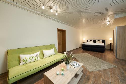 a living room with a green couch and a table at Landhotel Karrenberg in Kirchberg