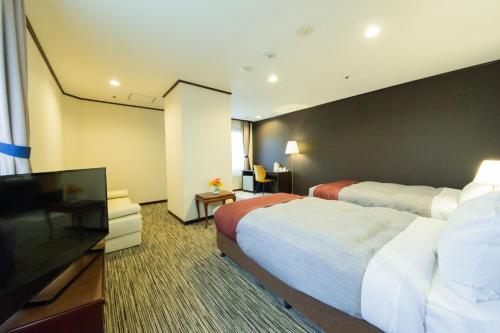 a hotel room with two beds and a flat screen tv at Garden hotel Shiunkaku Higashimatsuyama in Matsuyama