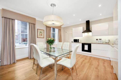 a dining room with a glass table and white chairs at No1 The Mansions By Mansley in London